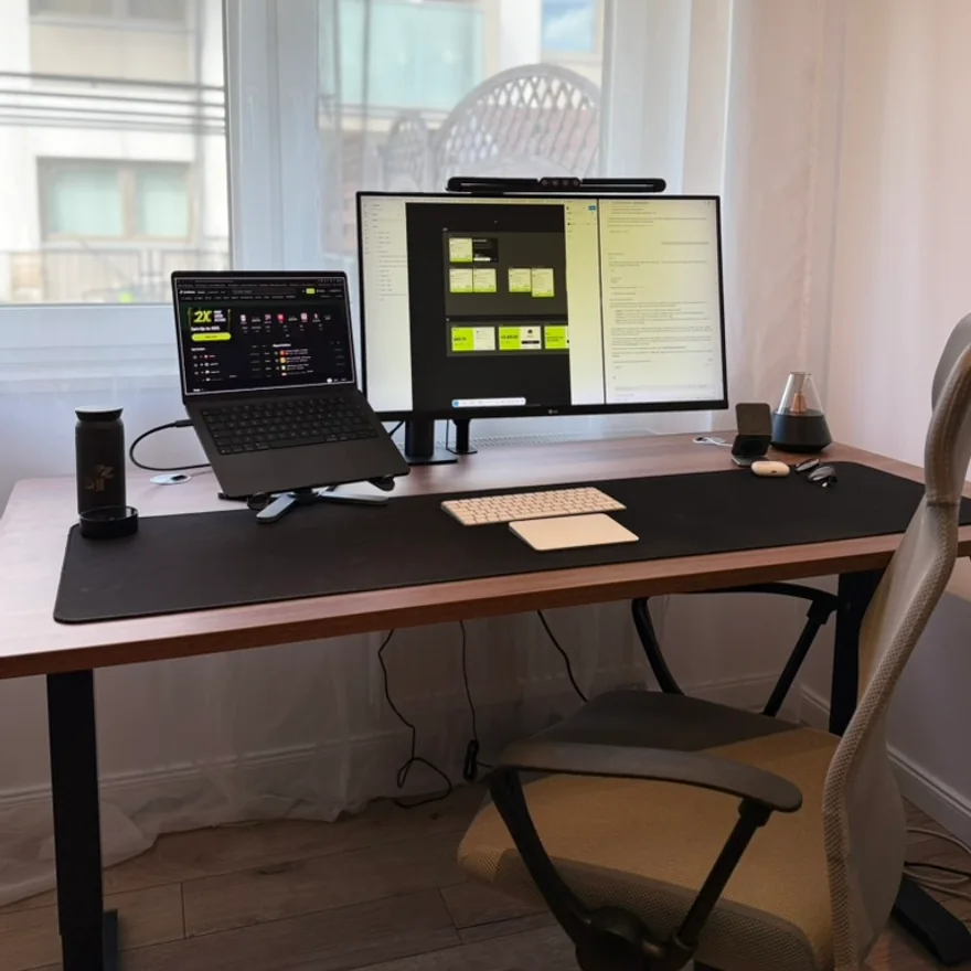 Max's desk: laptop, monitor and keyboard by a window